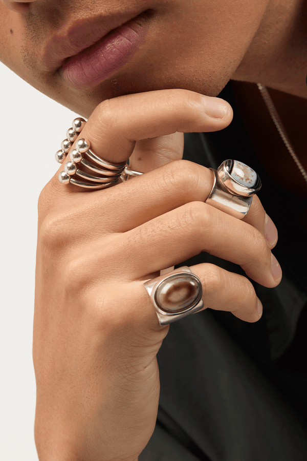 Model in statement silver rings with oval gemstones and ball details