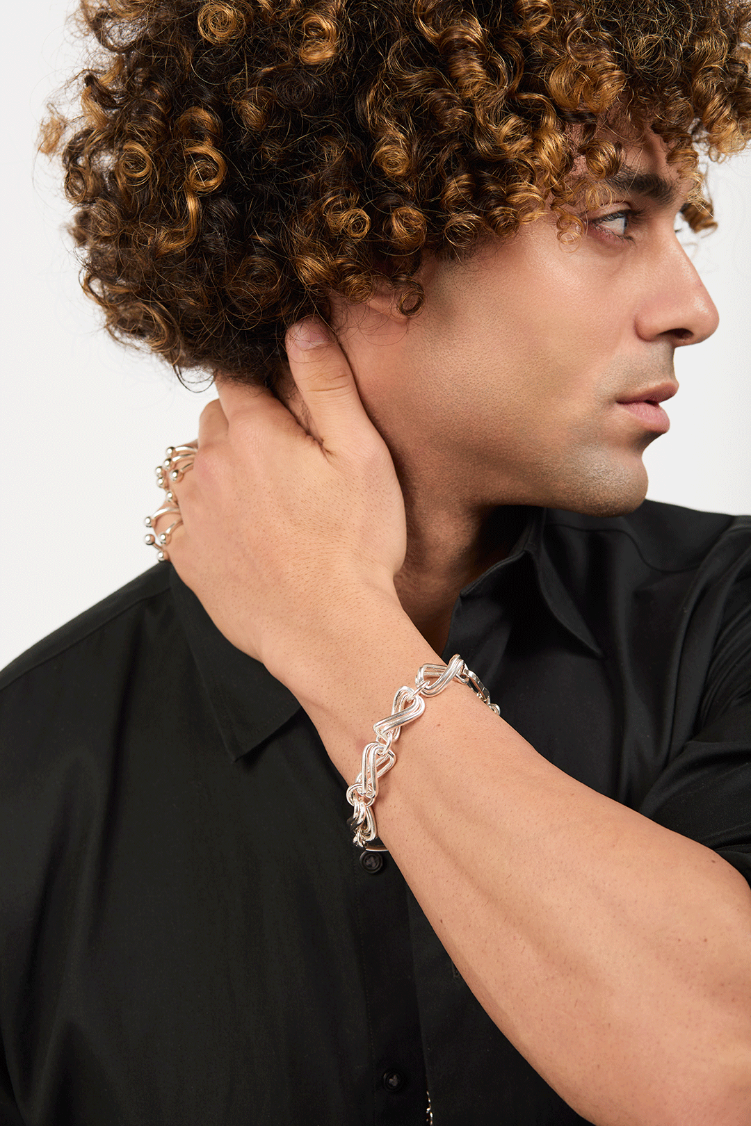 Man wearing silver rings and a bracelet made of interlocking infinity rings