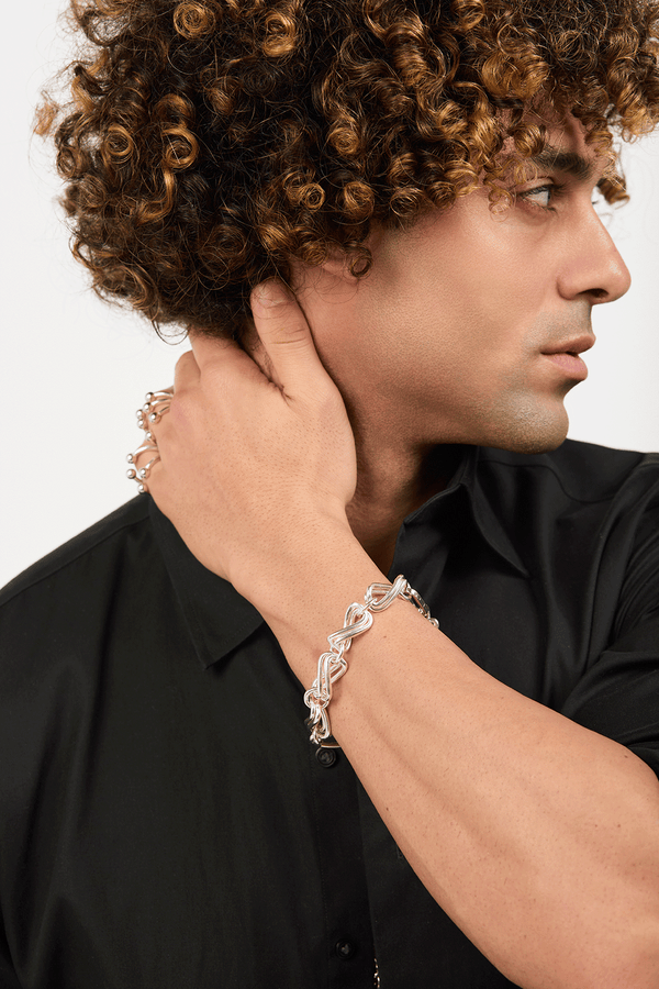 Man wearing silver rings and a bracelet made of interlocking infinity rings