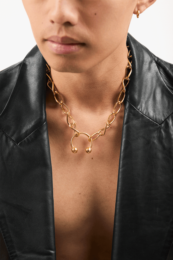 Model wearing a gold infinity loop necklace with piercing ring pendant